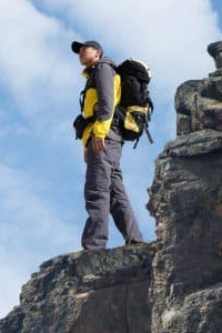 Hiker with backpack top of a mountain and enjoying valley view
